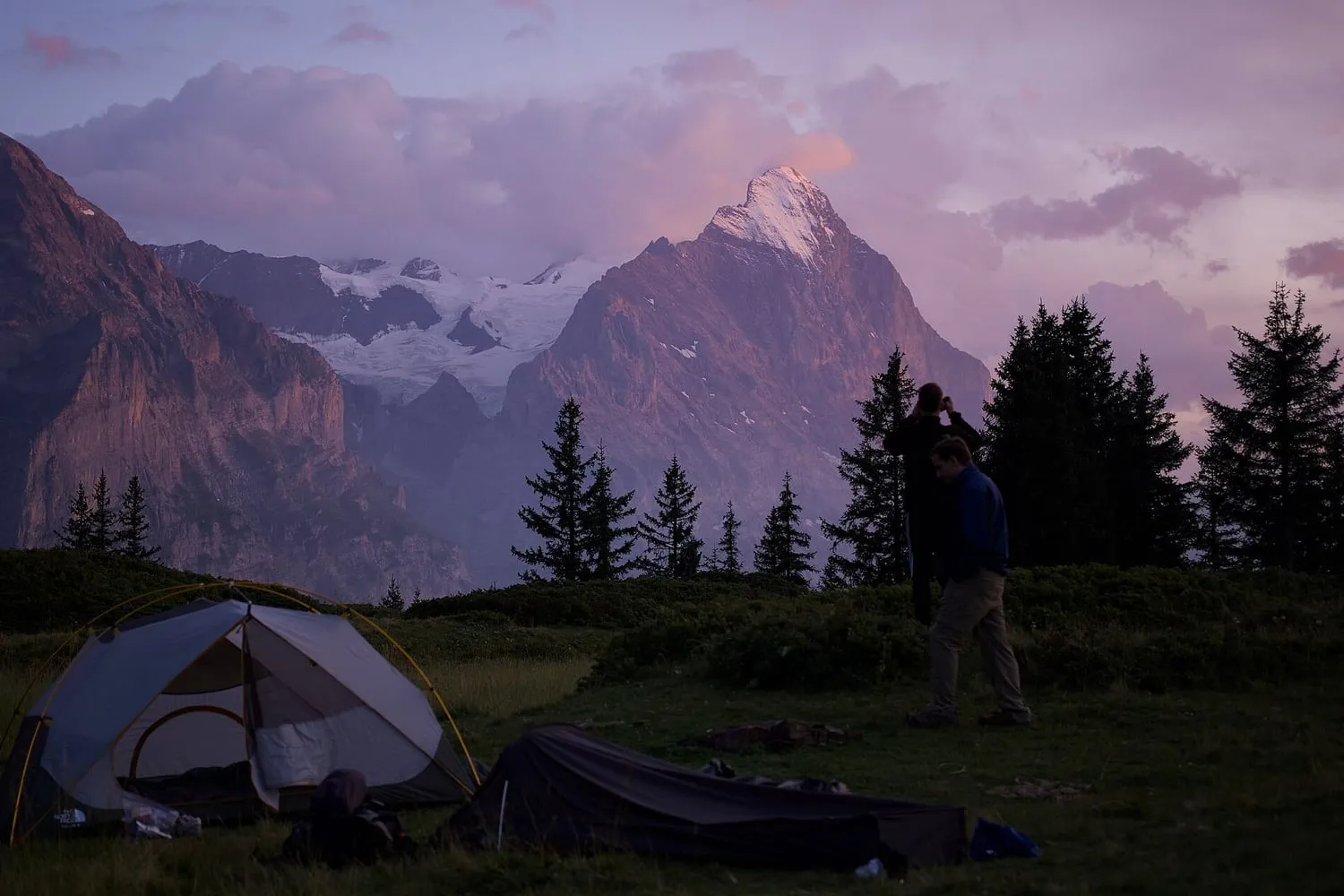 Tents pitched on a mountainside at dusk